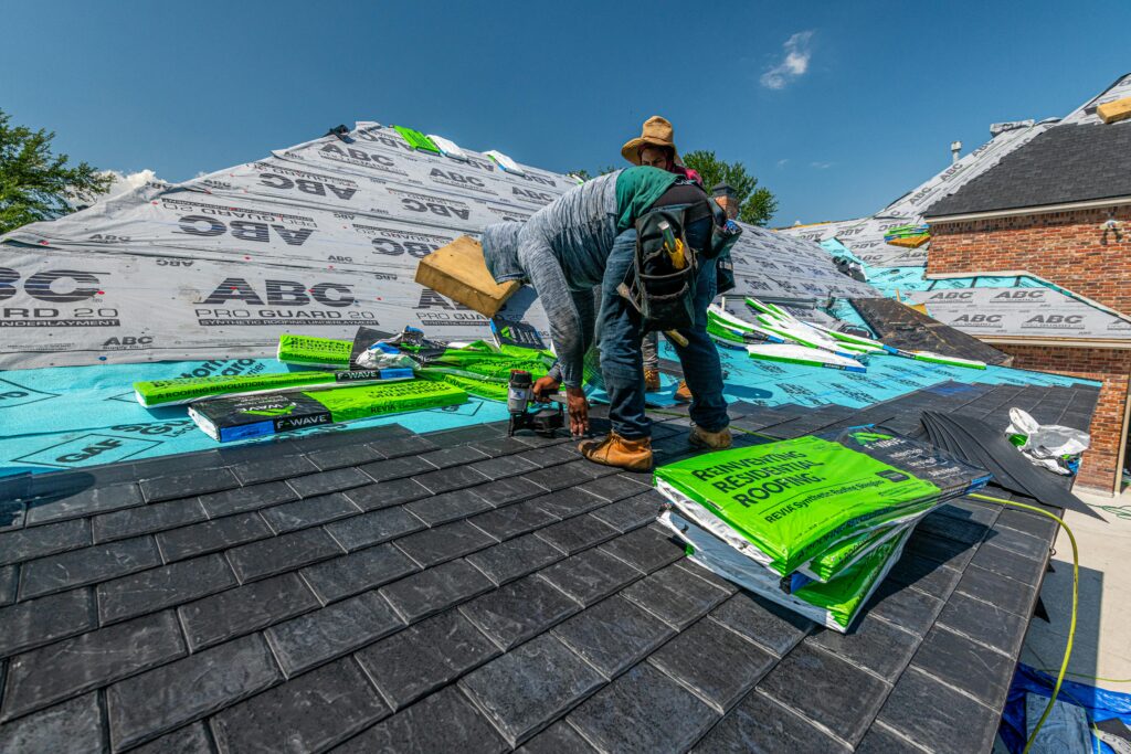 Workers installing a synthetic slate roof on a brick house in Fort Worth, Texas.